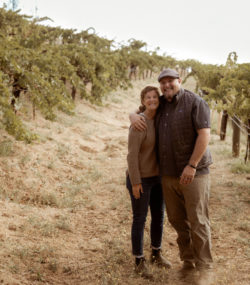 Matt Taylor and Macy Stubstad smiling together in Ink Grade Howell Mountain Vineyards, color, 2022