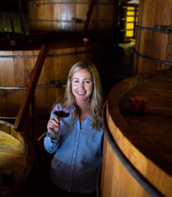 Winemaker Brittany Sherwood holding wine glass in cellar