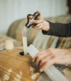 Hands use wine key on barrel in cellar