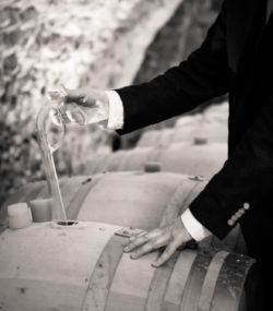 Hands use a wine key on a barrel in Roc de l'Abbaye cellar