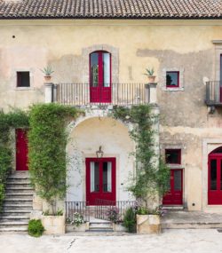 Zisola winery, white building with ivy and red doors and windows